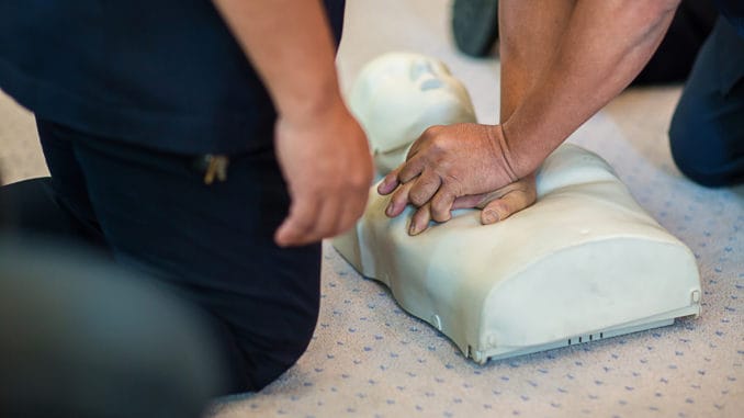 CPR training using and an AED and bag mask valve on an adult training manikin. First aid cardiopulmonary resuscitation course using automated external defibrillator device, AED.
