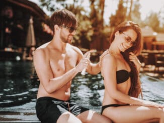 Young Beautiful Couple using Sunscreen at Poolside.