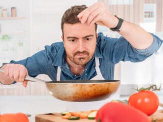 Cheerful young man preparing food at home