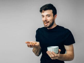 Casual looking guy hold bowl and some walnuts in hand