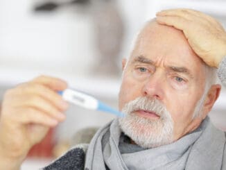 Senior man checking body temperature with thermometer