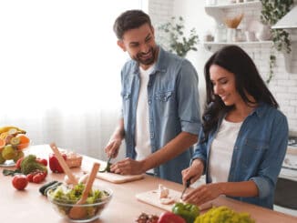 Caucasian couple preparing salad in the kitchen.