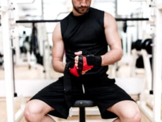 Man at gym preparing for workout, putting gloves on