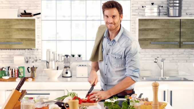 Happy handsome man cooking in kitchen at home.