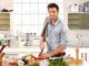 Happy handsome man cooking in kitchen at home.